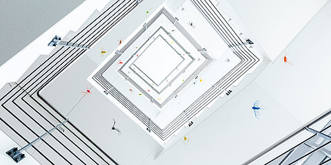 Treppenhaus mit Kunstinstallation in Form von bunten Vögeln