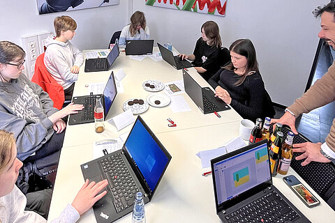 Six girls together with Coroplast Group apprentice Tim Potempa in front of their laptops.