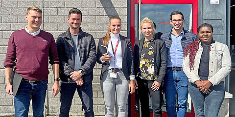 Six employees in front of the Coroplast Tape production building