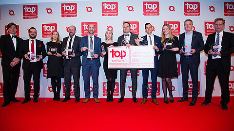 People in suits at award ceremony on red carpet