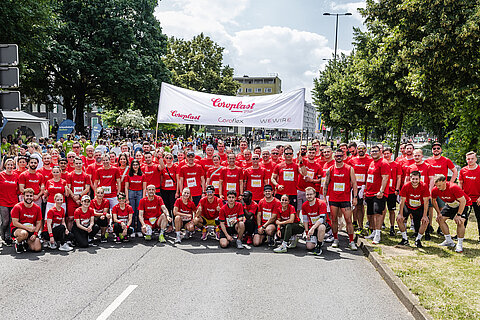 Teilnehmende der Coroplast Group beim Schwebebahnlauf 2024 posieren vor dem Start des Laufs gemeinsam auf der Laufstrecke